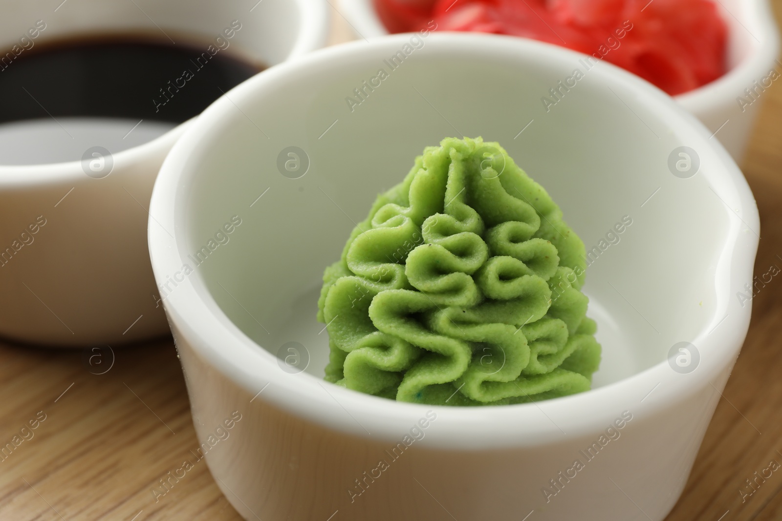 Photo of Hot wasabi paste in bowl on wooden table, closeup