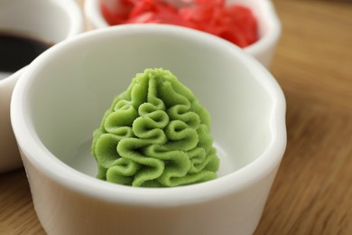 Photo of Hot wasabi paste in bowl on wooden table, closeup