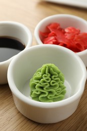 Photo of Hot wasabi paste, soy sauce and ginger on wooden table, closeup