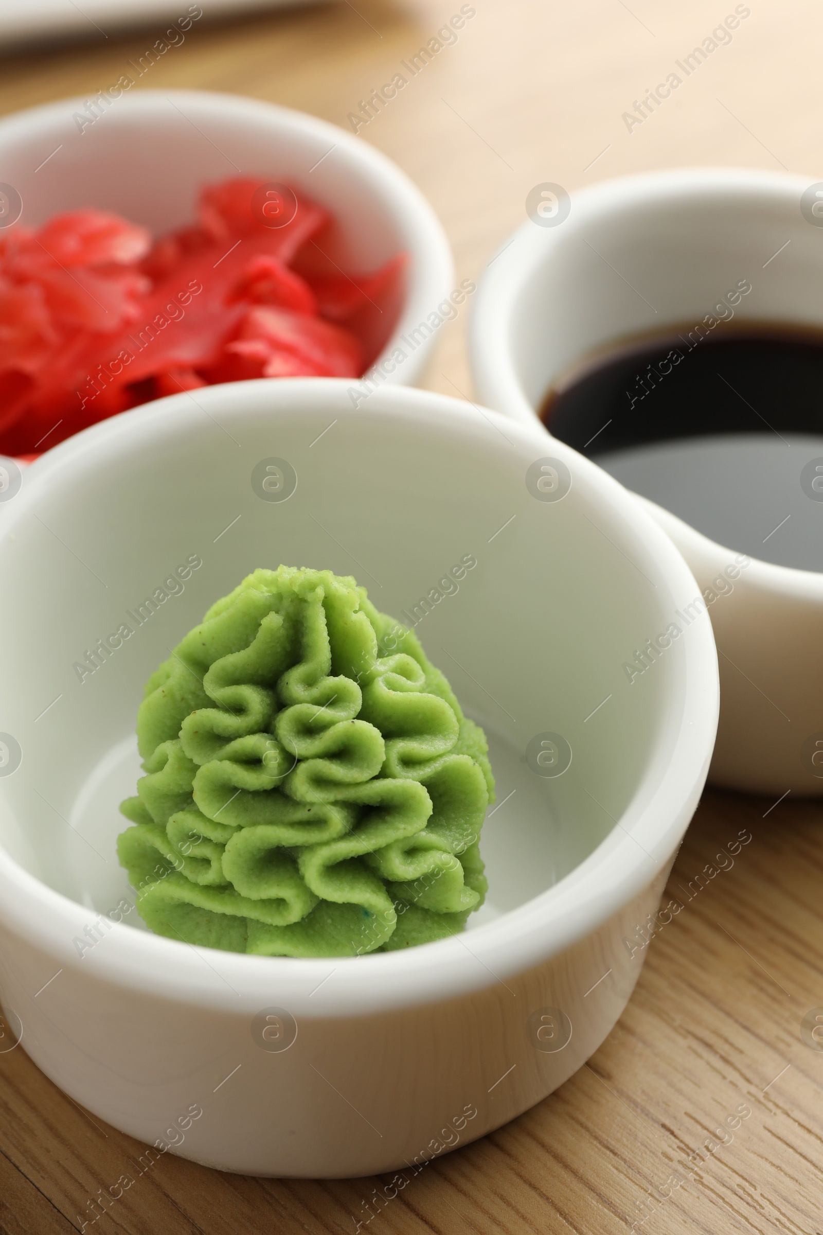 Photo of Hot wasabi paste, soy sauce and ginger on wooden table, closeup