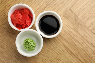 Photo of Hot wasabi paste, soy sauce and ginger on wooden table, flat lay. Space for text