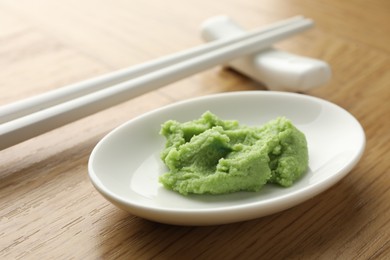 Photo of Hot wasabi paste and chopsticks on wooden table, closeup