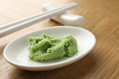 Photo of Hot wasabi paste and chopsticks on wooden table, closeup