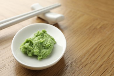 Photo of Hot wasabi paste and chopsticks on wooden table, closeup. Space for text