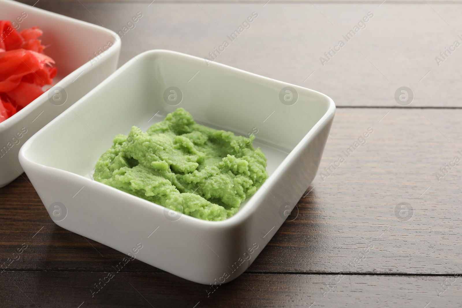 Photo of Hot wasabi paste and ginger on wooden table, closeup