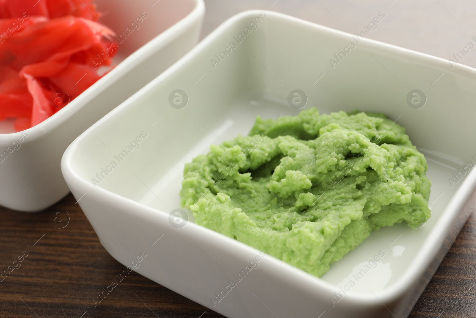 Photo of Hot wasabi paste and ginger on wooden table, closeup