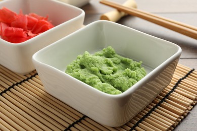 Photo of Hot wasabi paste, ginger and chopsticks on wooden table, closeup