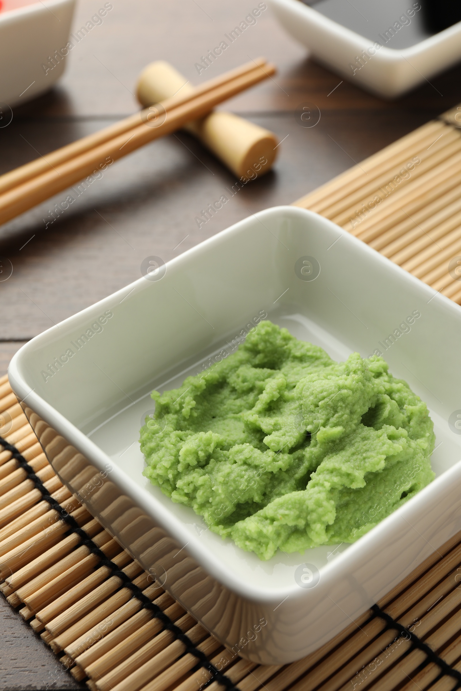 Photo of Hot wasabi paste and chopsticks on wooden table, closeup