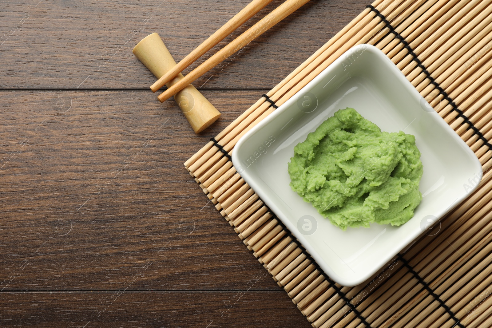 Photo of Hot wasabi paste and chopsticks on wooden table, top view. Space for text