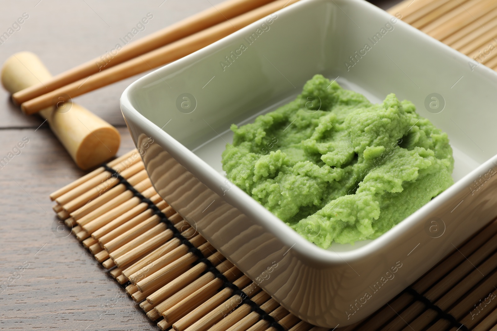 Photo of Hot wasabi paste and chopsticks on wooden table, closeup