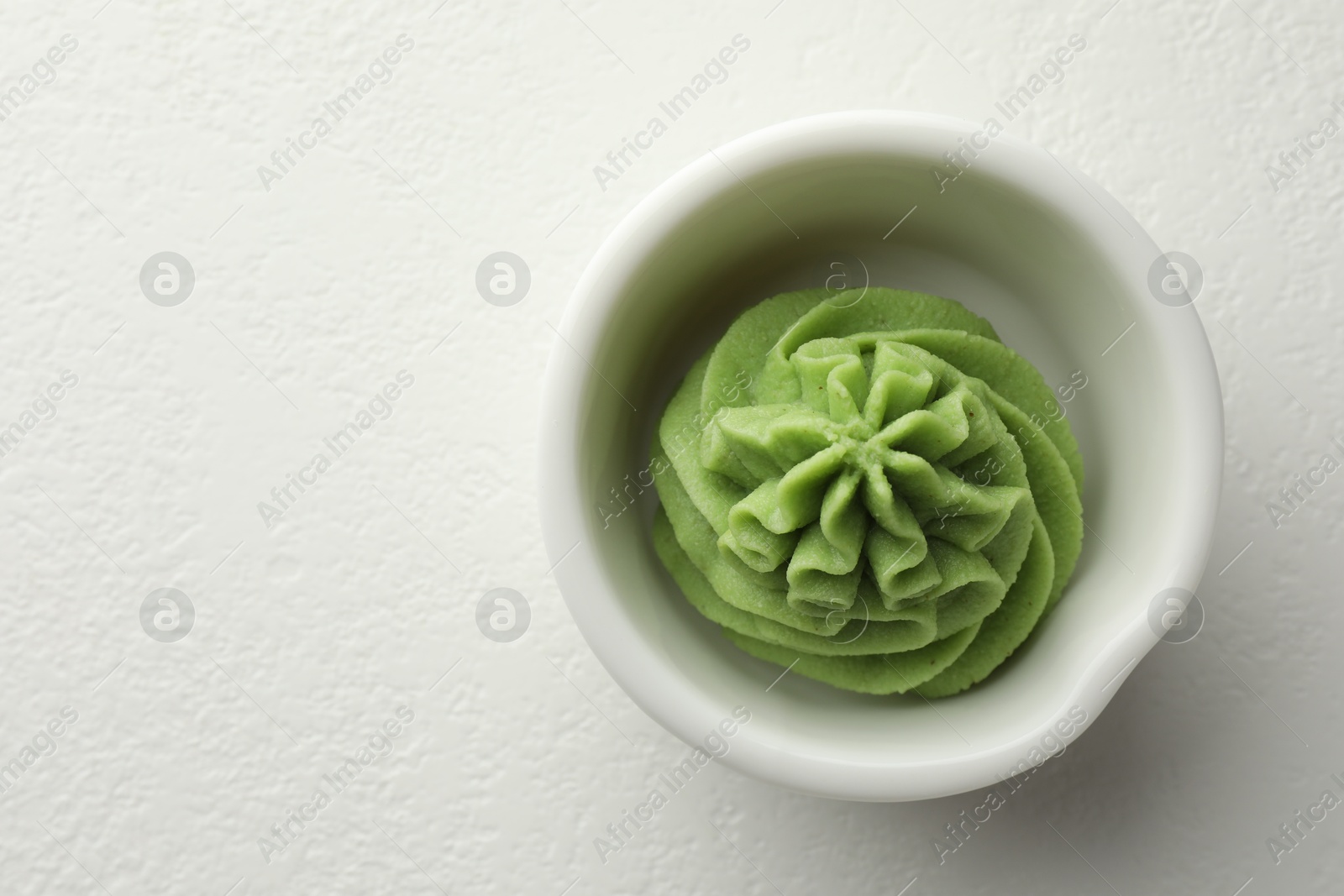 Photo of Hot wasabi paste in bowl on white table, top view. Space for text