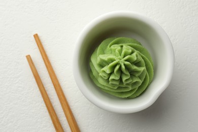 Photo of Hot wasabi paste in bowl and chopsticks on white table, top view