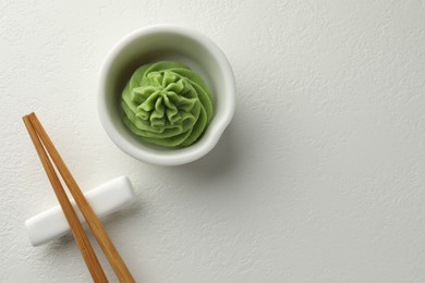 Photo of Hot wasabi paste in bowl and chopsticks on white table, top view. Space for text