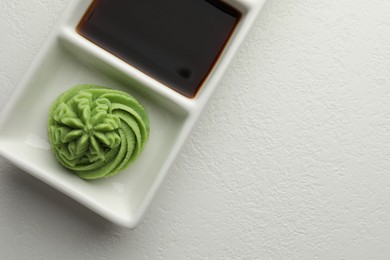 Photo of Hot wasabi paste and soy sauce on white table, top view. Space for text