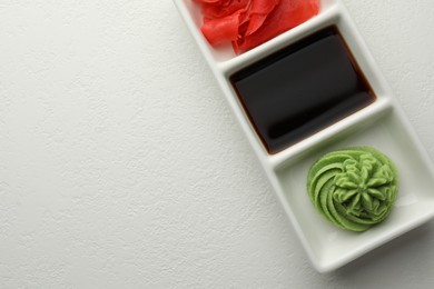 Photo of Hot wasabi paste, soy sauce and ginger on white table, top view. Space for text