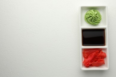 Photo of Hot wasabi paste, soy sauce and ginger on white table, top view. Space for text