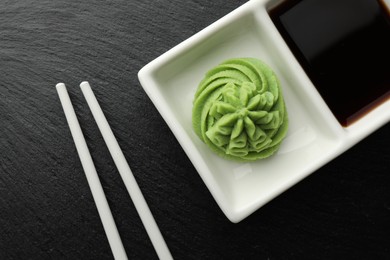 Photo of Hot wasabi paste, soy sauce and chopsticks on grey table, top view