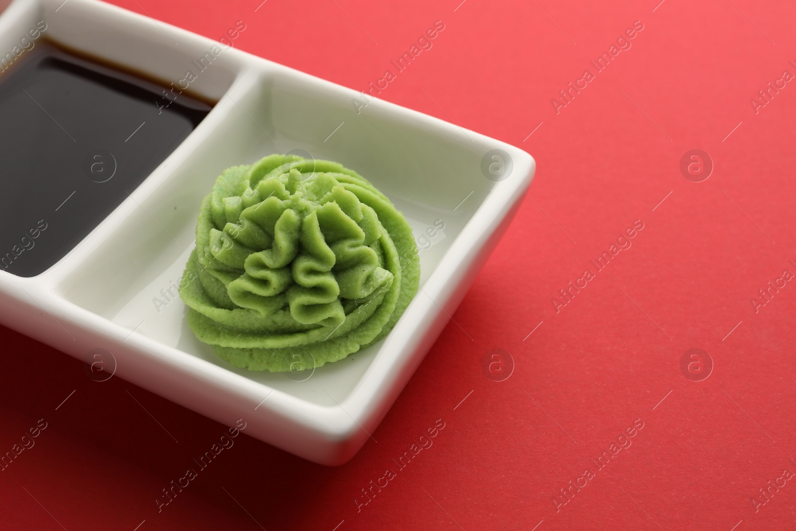 Photo of Hot wasabi paste and soy sauce on red table, closeup. Space for text