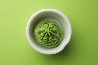 Photo of Hot wasabi paste in bowl on green table, top view