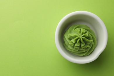 Photo of Hot wasabi paste in bowl on green table, top view. Space for text