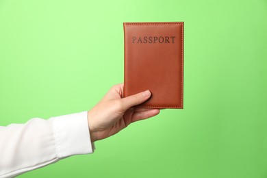 Photo of Woman holding passport in bright cover on green background, closeup