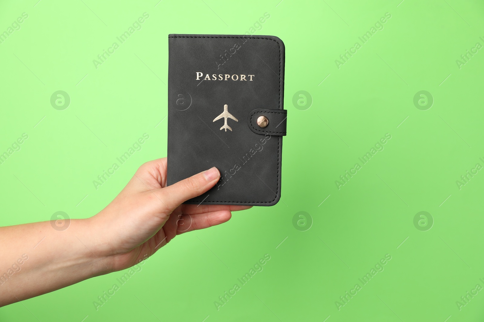 Photo of Woman holding passport in bright cover on green background, closeup. Space for text