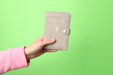 Photo of Woman holding passport in bright cover on green background, closeup. Space for text