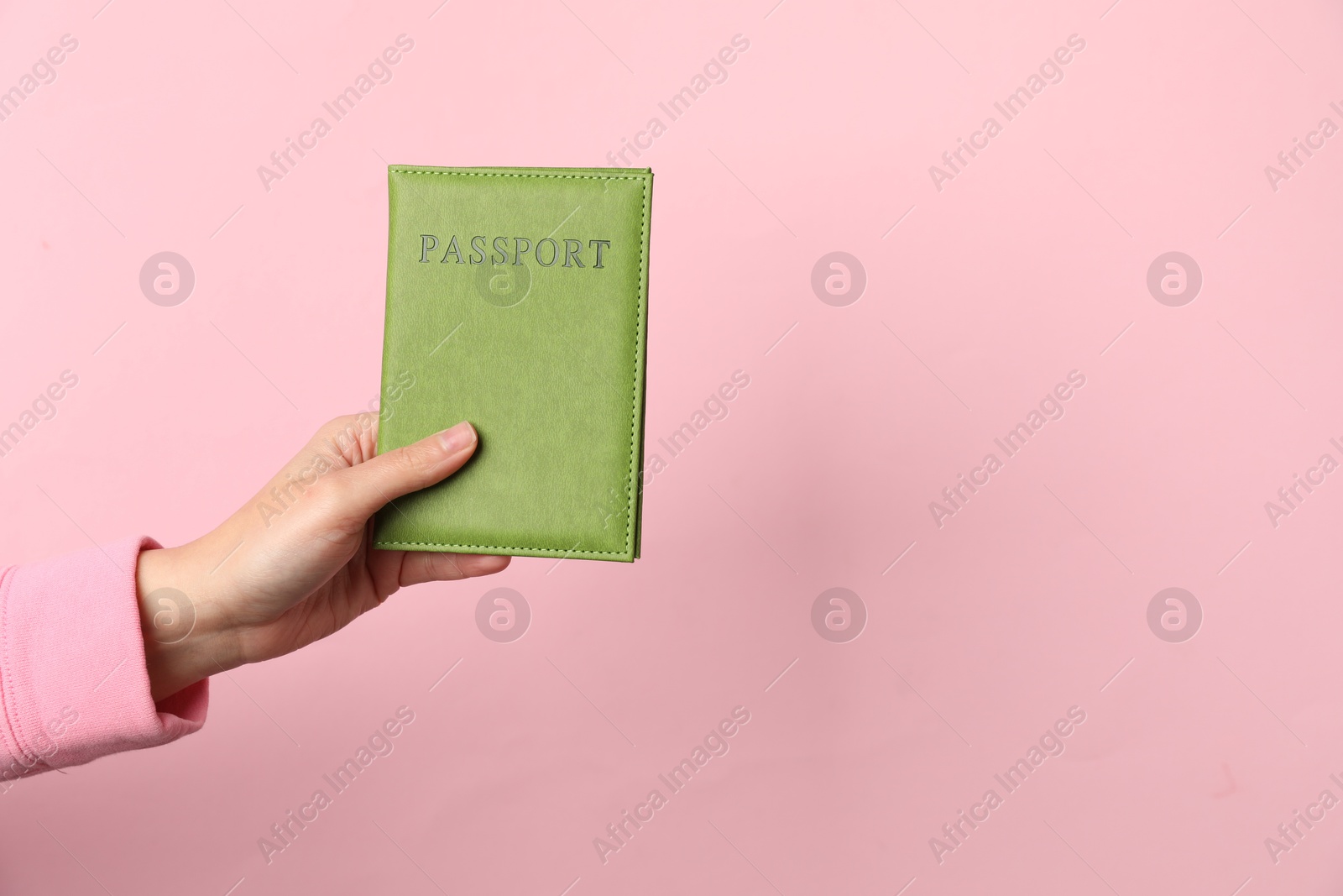 Photo of Woman holding passport in bright cover on pink background, closeup. Space for text