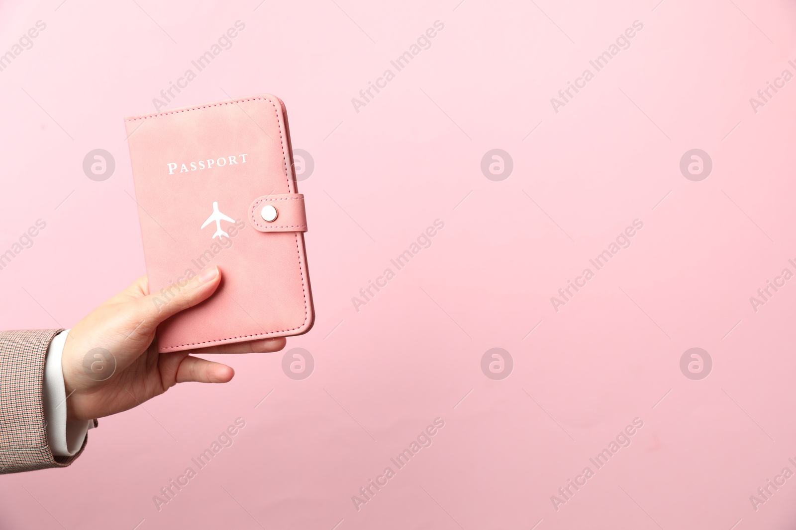 Photo of Woman holding passport in bright cover on pink background, closeup. Space for text