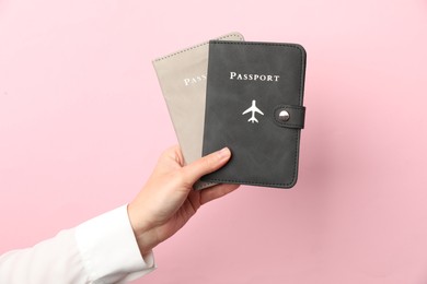 Photo of Woman holding passports in bright covers on pink background, closeup