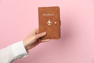 Photo of Woman holding passport in bright cover on pink background, closeup