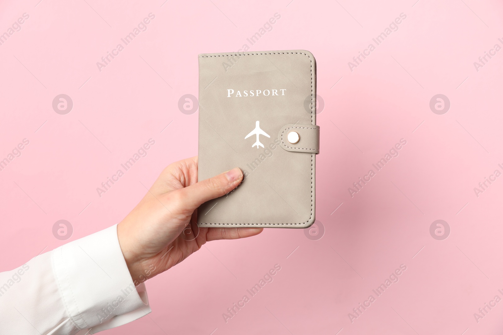 Photo of Woman holding passport in bright cover on pink background, closeup