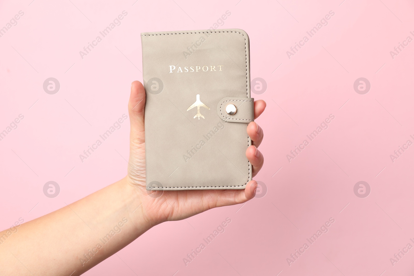 Photo of Woman holding passport in bright cover on pink background, closeup