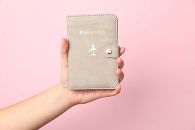 Photo of Woman holding passport in bright cover on pink background, closeup