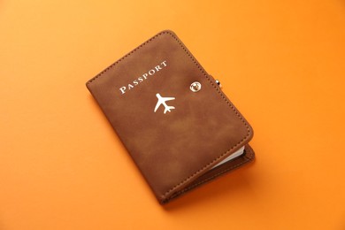 Photo of Passport in leather cover on orange background, closeup