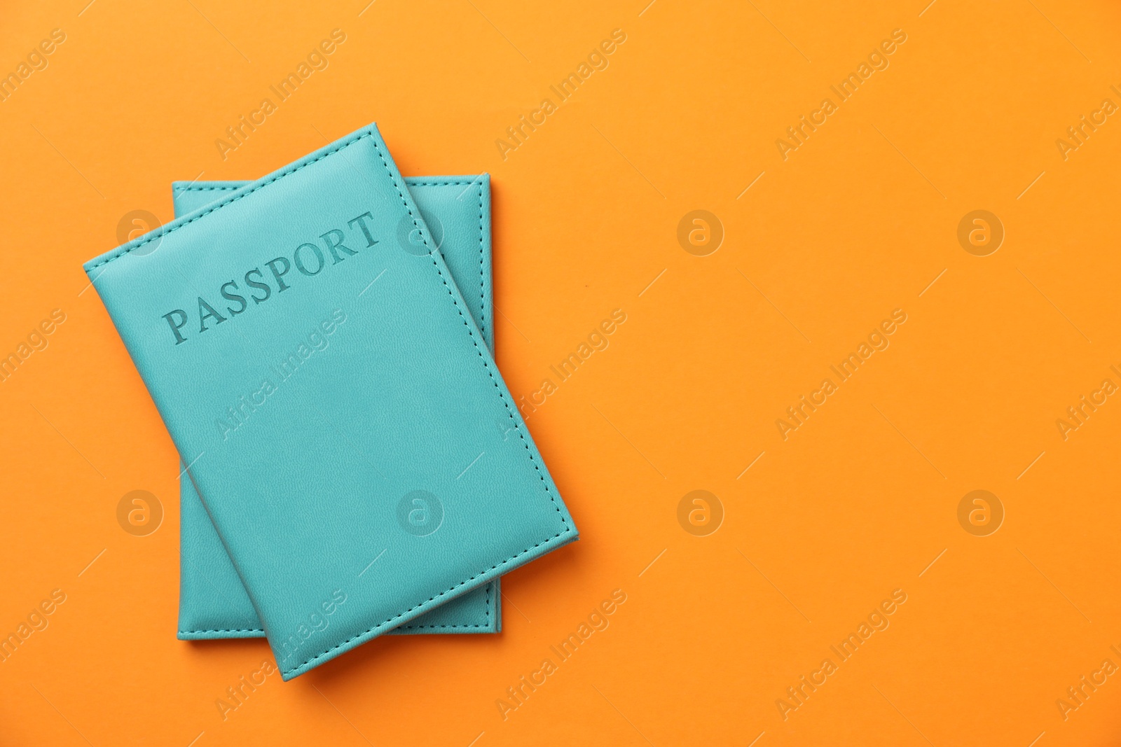 Photo of Passports in bright covers on orange background, top view. Space for text