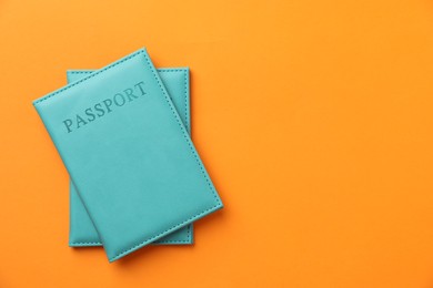 Photo of Passports in bright covers on orange background, top view. Space for text