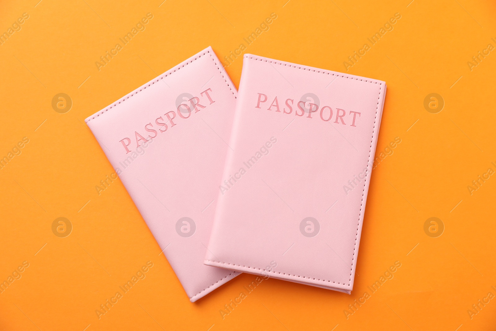 Photo of Passports in bright covers on orange background, top view