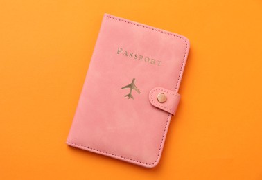 Photo of Passport in bright cover on orange background, top view