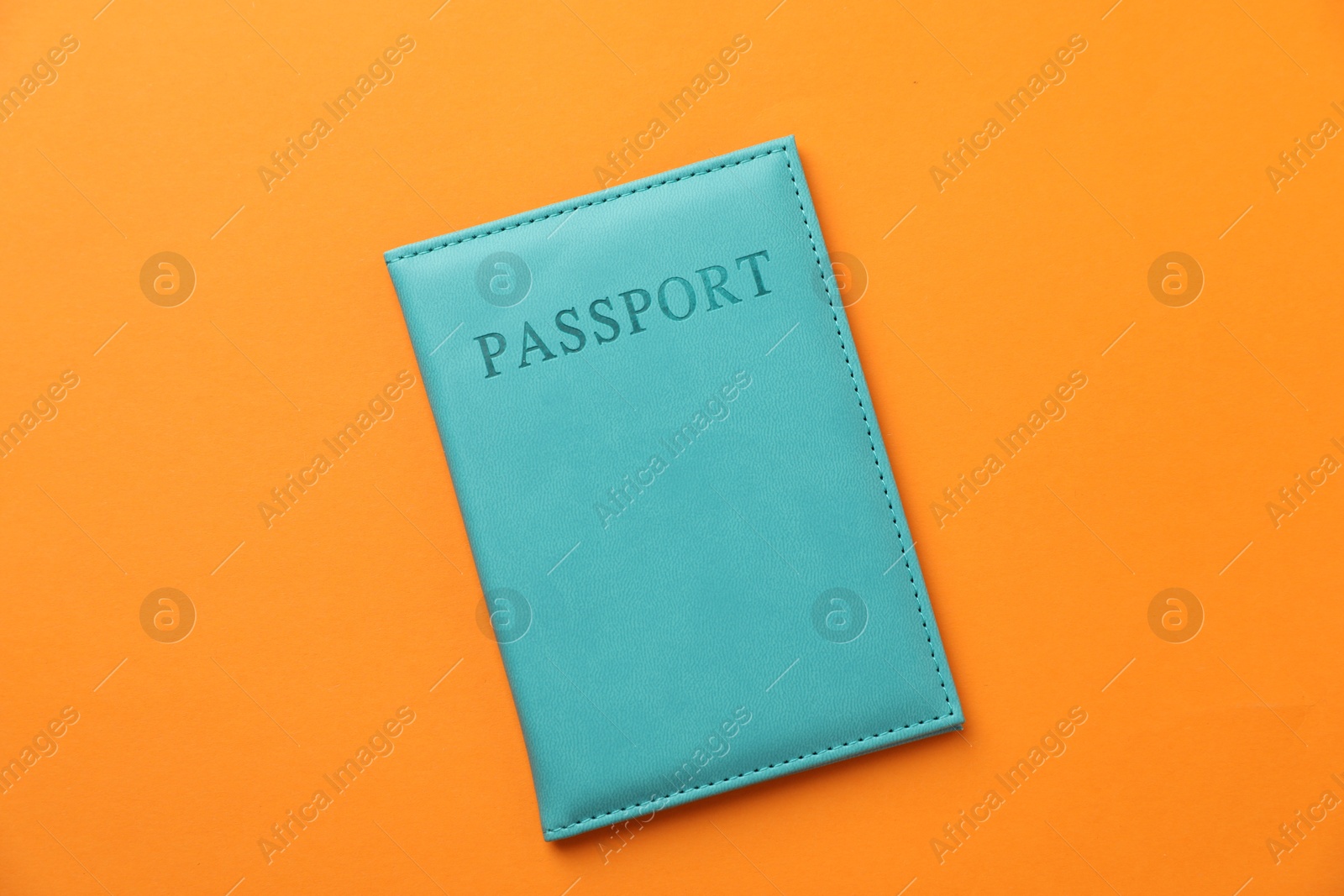 Photo of Passport in bright cover on orange background, top view