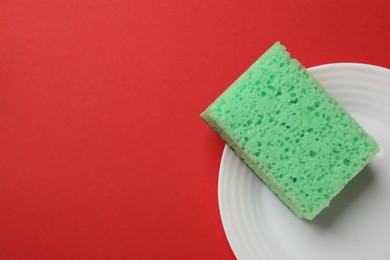 Photo of Plate with sponge on red background, top view. Space for text