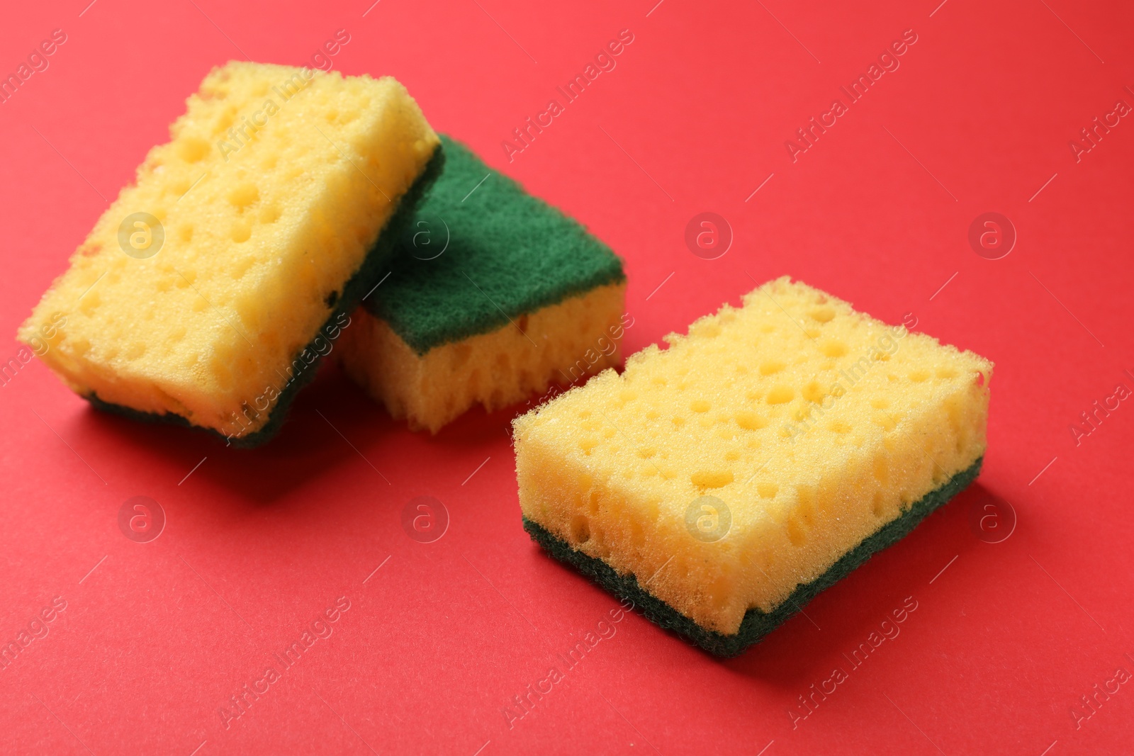 Photo of Soft sponges on red background. Cleaning tool