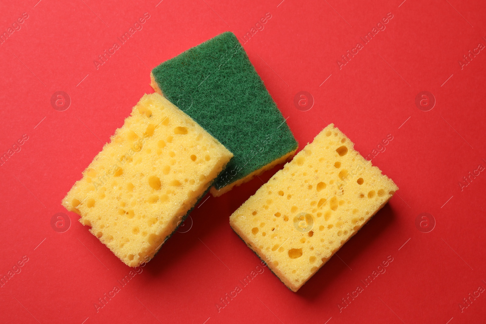 Photo of Soft sponges on red background, flat lay. Cleaning tool