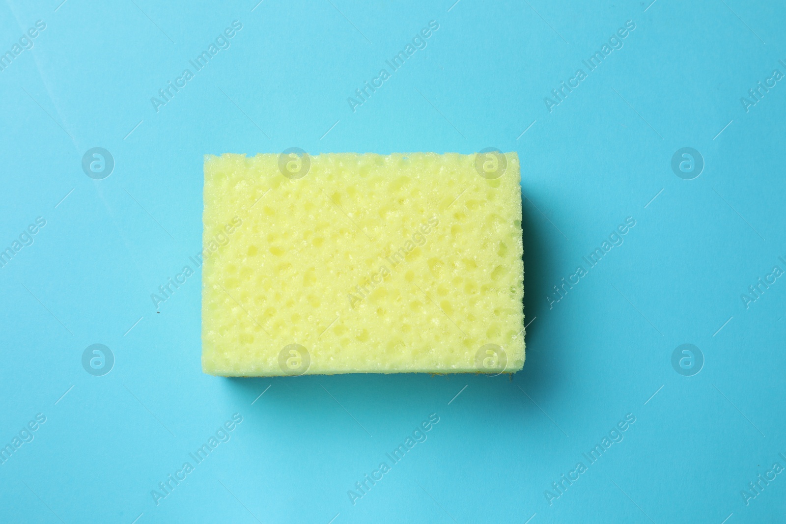 Photo of Soft sponge on light blue background, top view. Cleaning tool