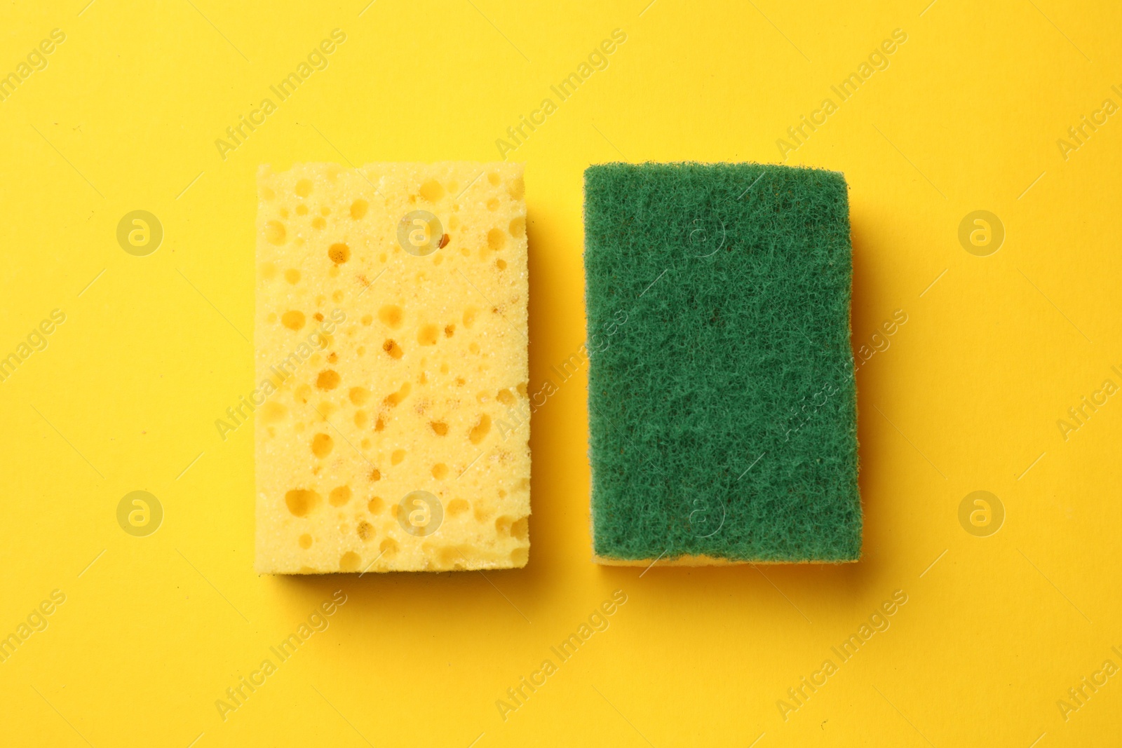 Photo of Soft sponges on yellow background, top view. Cleaning tool