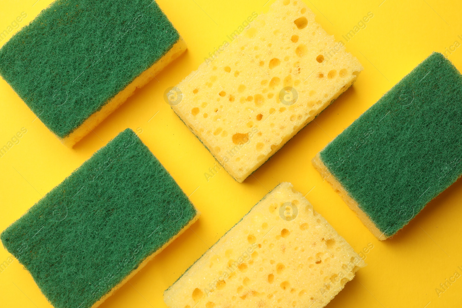 Photo of Soft sponges on yellow background, flat lay. Cleaning tool