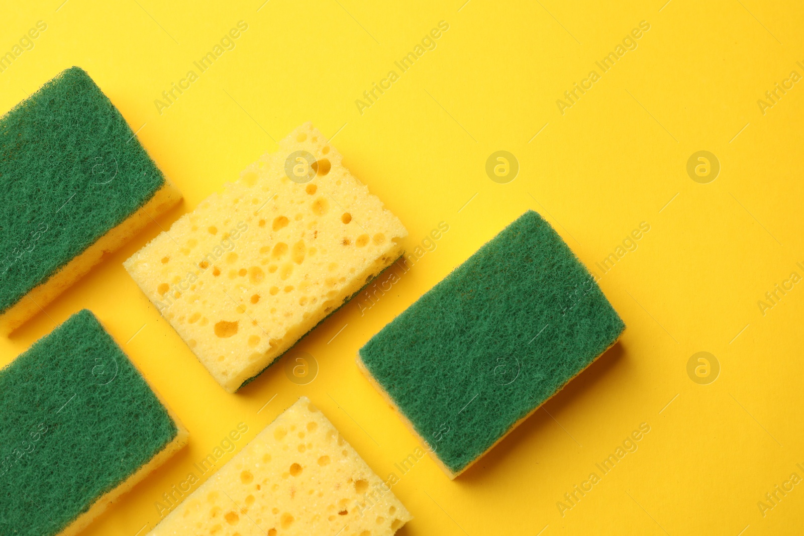 Photo of Soft sponges on yellow background, flat lay. Cleaning tool