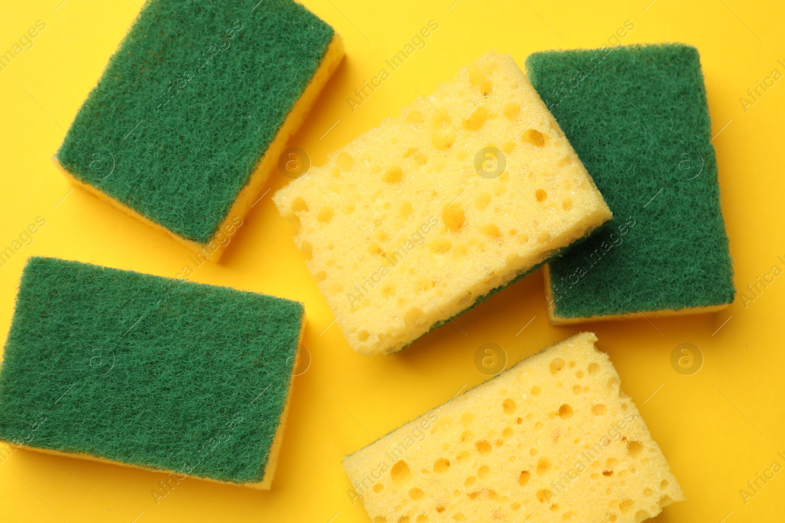 Photo of Soft sponges on yellow background, flat lay. Cleaning tool