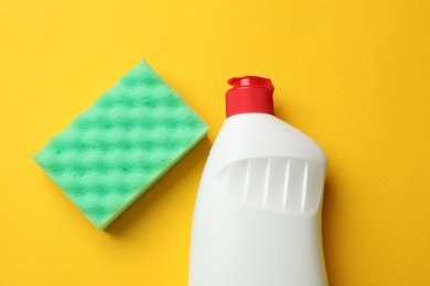 Photo of Sponge and dish soap on yellow background