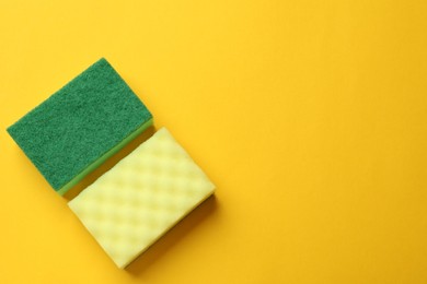 Photo of Soft sponges on yellow background, top view with space for text. Cleaning tool